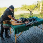 A lady giving another lady a massage on the deck at Rhulani Safari Lodge